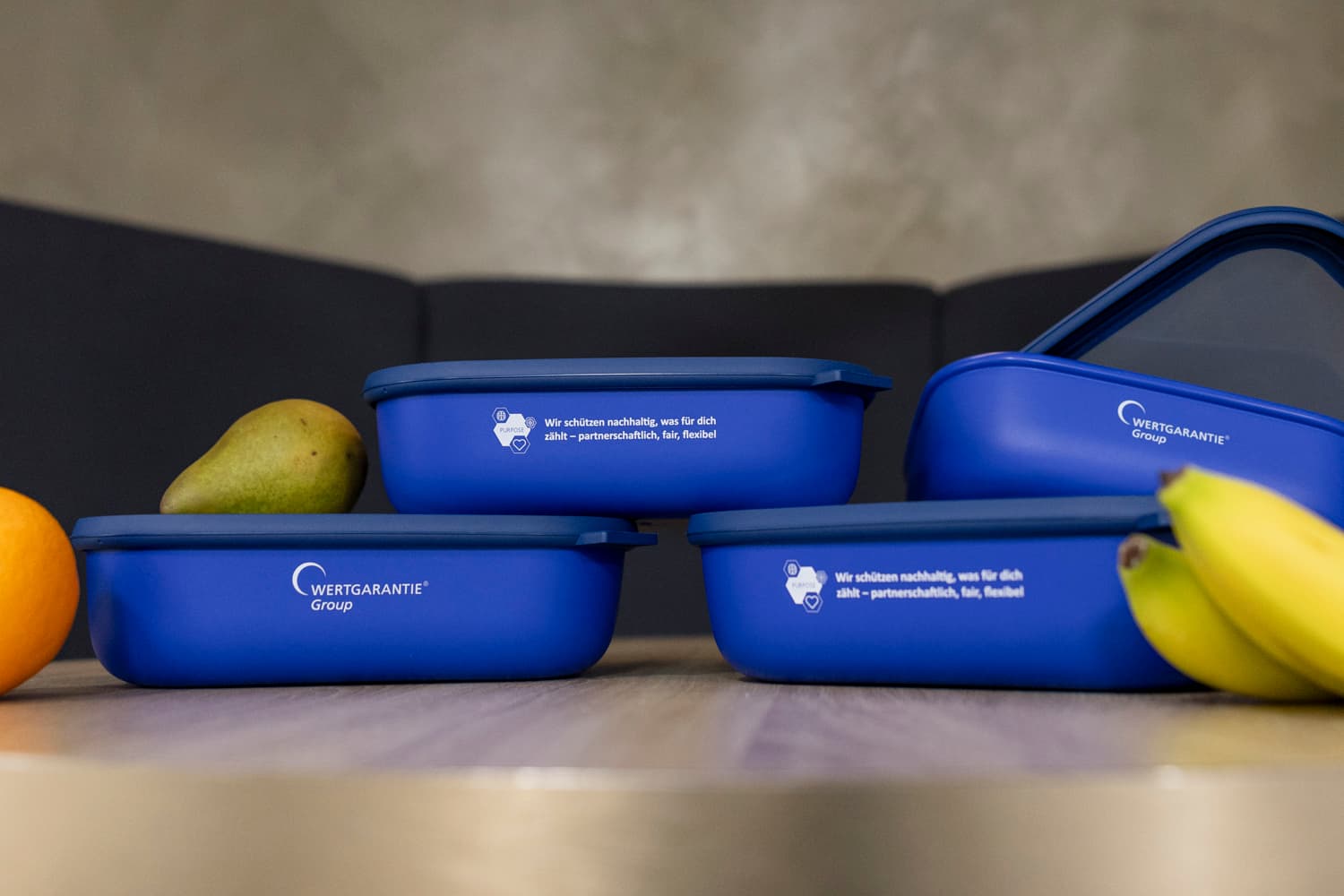 Lunchboxen Vier Lunchboxen sind neben Obst übereinander gestapelt